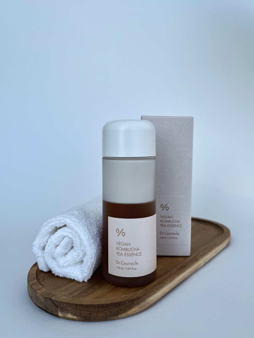 Amber skincare bottles and folded towel on a wooden tray